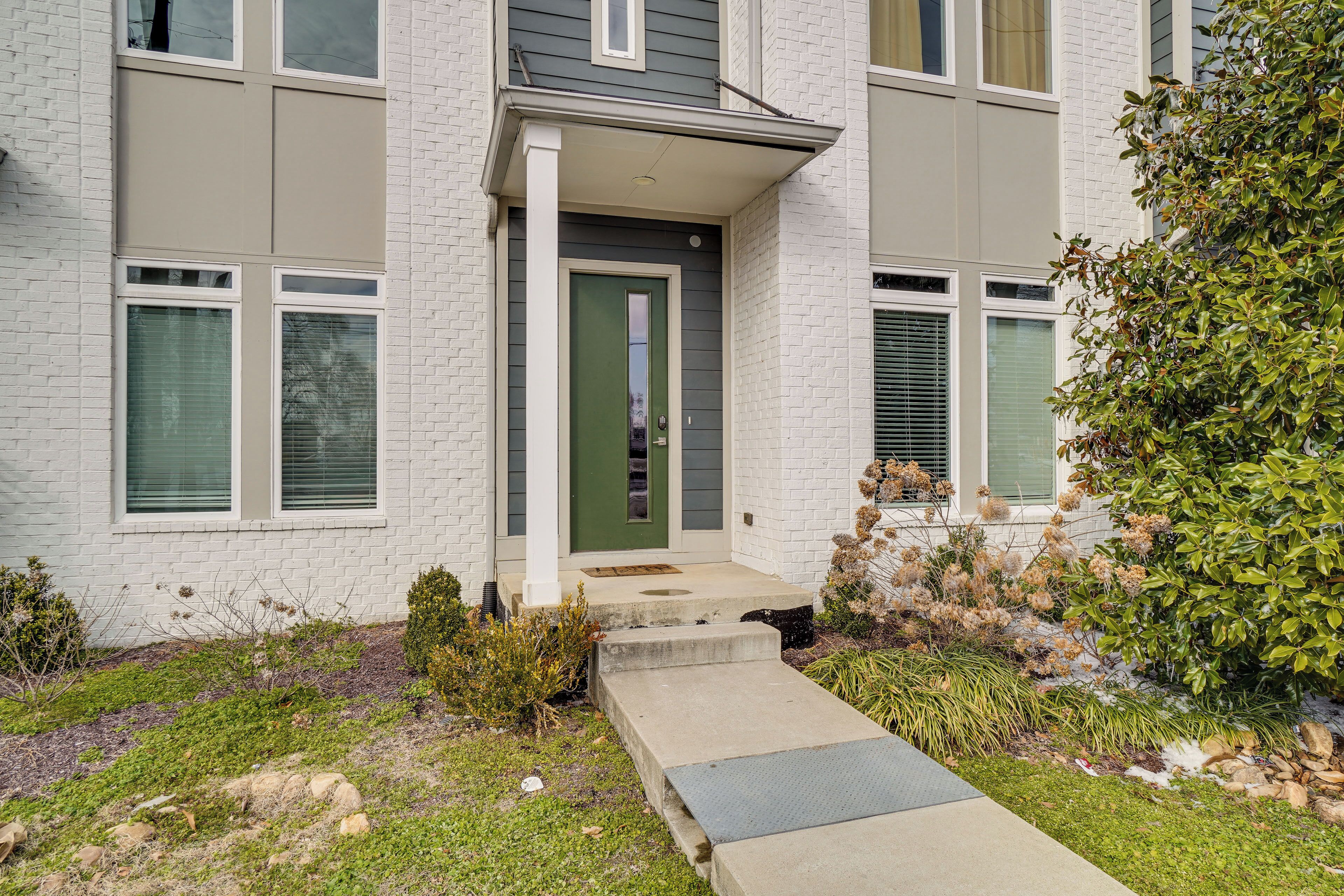 A two-story building with a green door and white brick exterior.