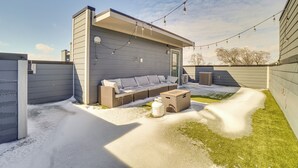 A modern outdoor seating area with a sofa and cushions, a small table, and a propane tank. - 1 Mi to Nashville General: Upscale Townhome (Nashville)