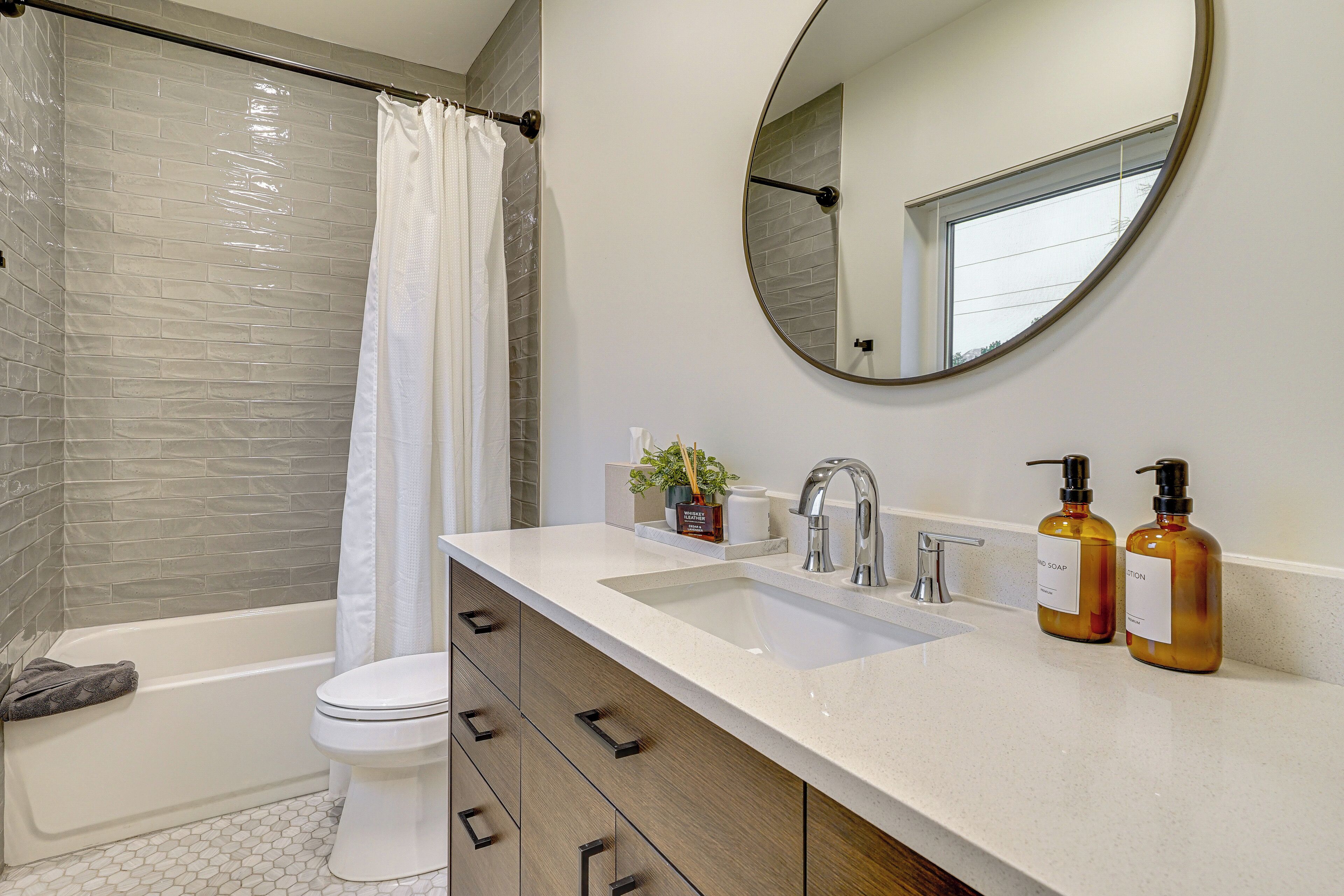 A modern bathroom with a bathtub, toilet, sink, and a mirror.