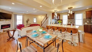 A spacious living area with a fireplace, a dining table set with blue plates, and a kitchen with a stone backsplash. - Walk to Kinnickinnic Ave! Newly Updated Abode (Milwaukee)