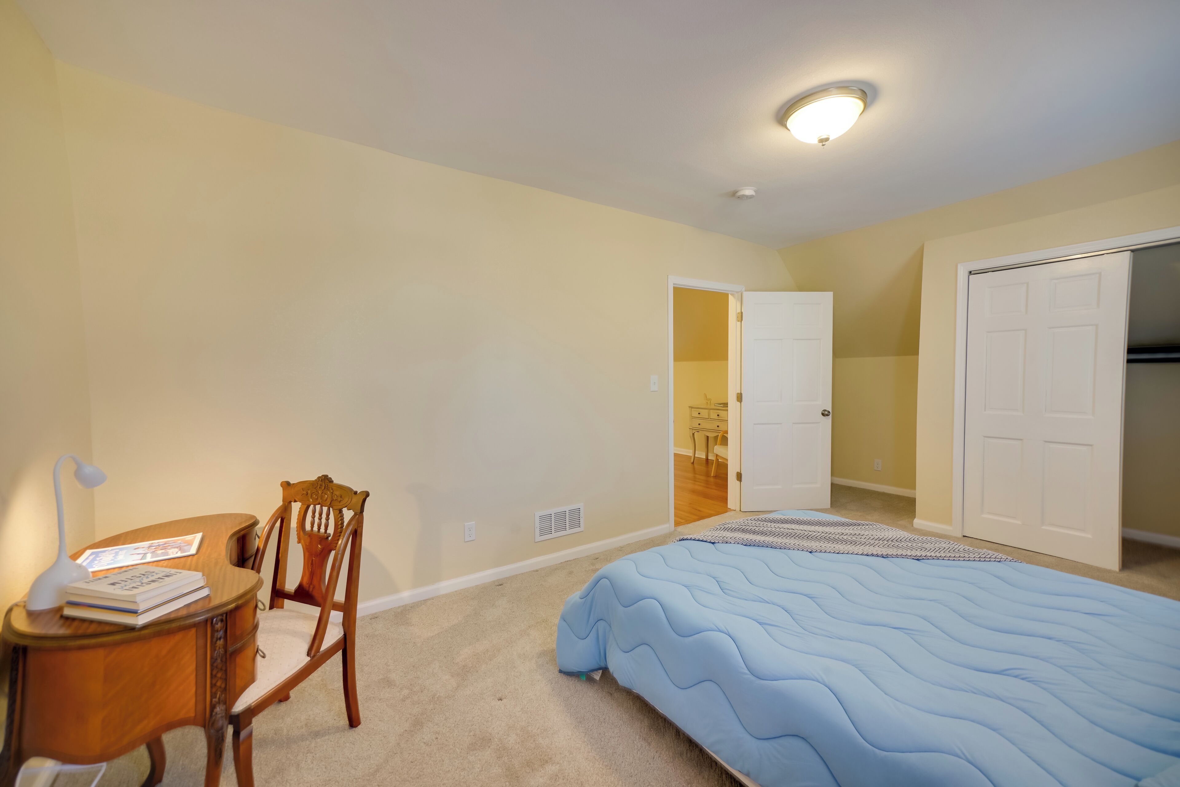 A bedroom with a bed, a desk with a chair, and a wardrobe.