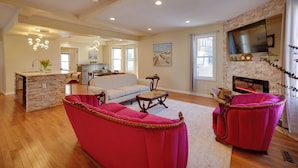 A spacious living room with a fireplace, a kitchen area, and a dining space. - Walk to Kinnickinnic Ave! Newly Updated Abode (Milwaukee)