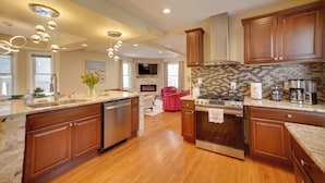 A modern kitchen with wooden cabinets, stainless steel appliances, and a large island. - Walk to Kinnickinnic Ave! Newly Updated Abode (Milwaukee)