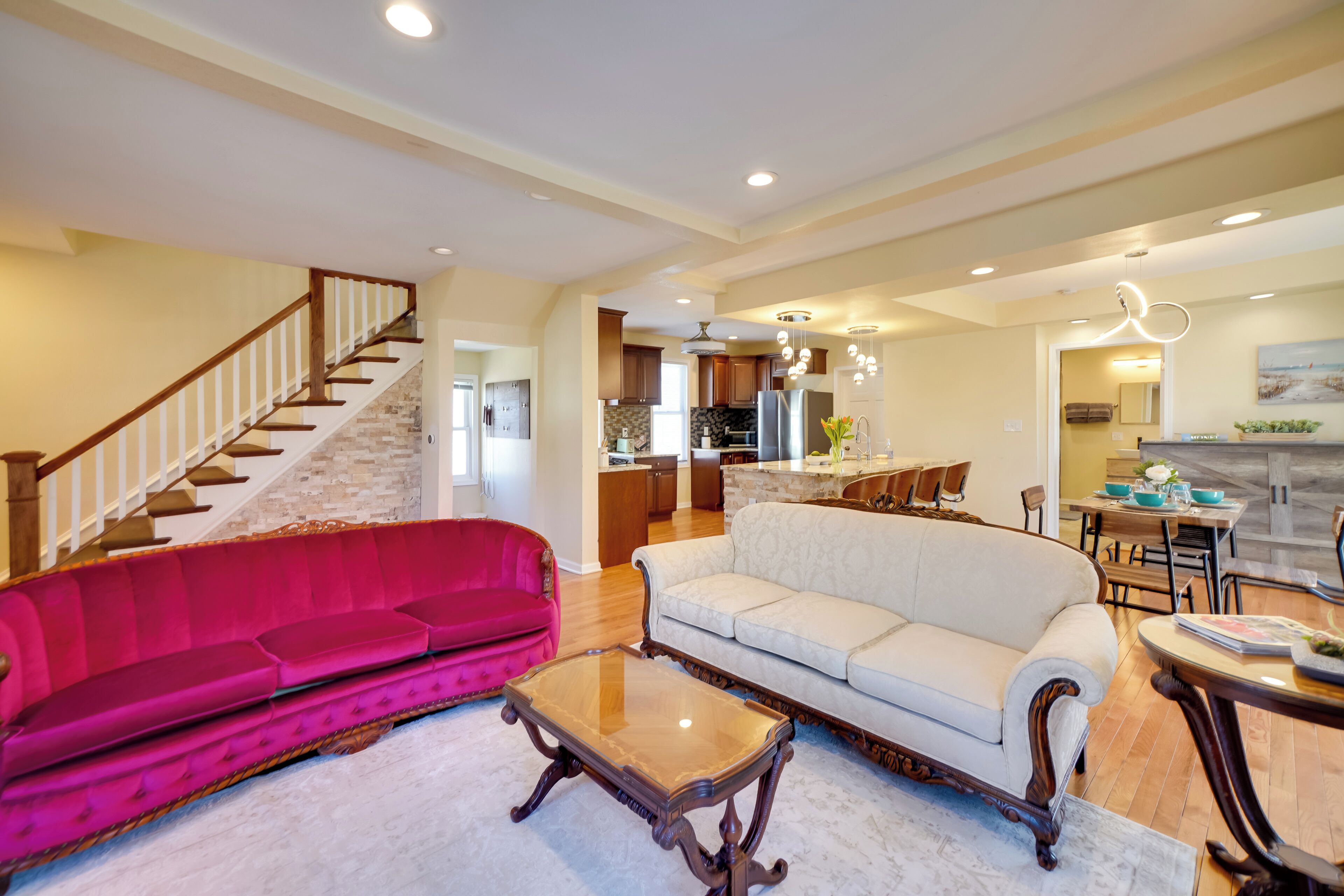 A spacious living area with a staircase, a kitchen, and a dining area.