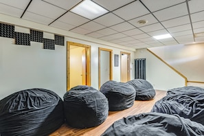 Une pièce avec des fauteuils en forme de haricots noirs, un plancher en bois et un escalier.