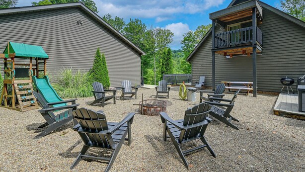 Un jardin avec un foyer, des fauteuils Adirondack, un toboggan et un espace barbecue.