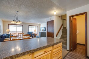 A kitchen with granite countertops, wooden cabinets, and a dining area with a table and chairs. - Pool & Hot Tub! Hub for All-season Winter Park Fun (Winter Park)