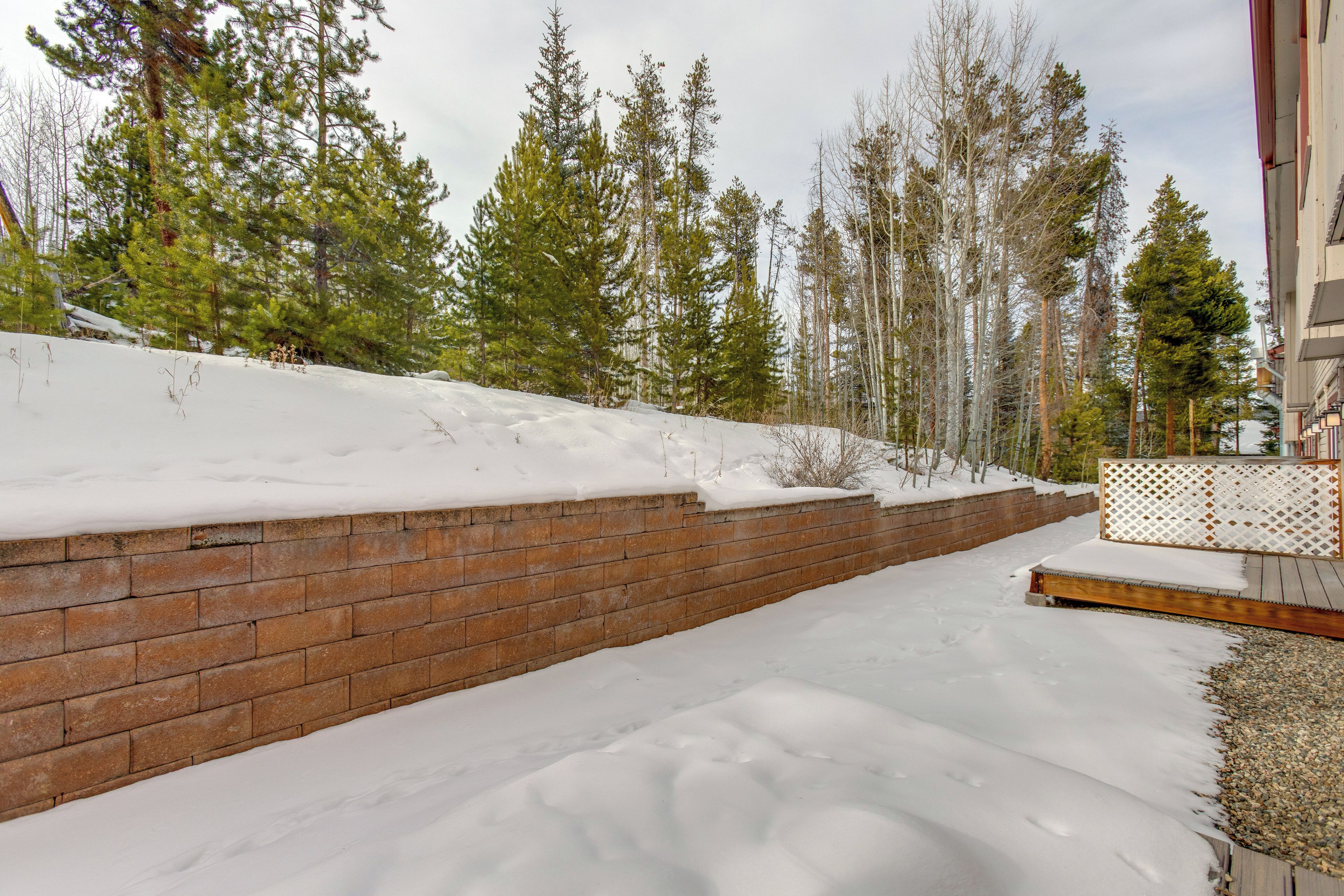 A snow-covered outdoor area with a brick wall and wooden deck.