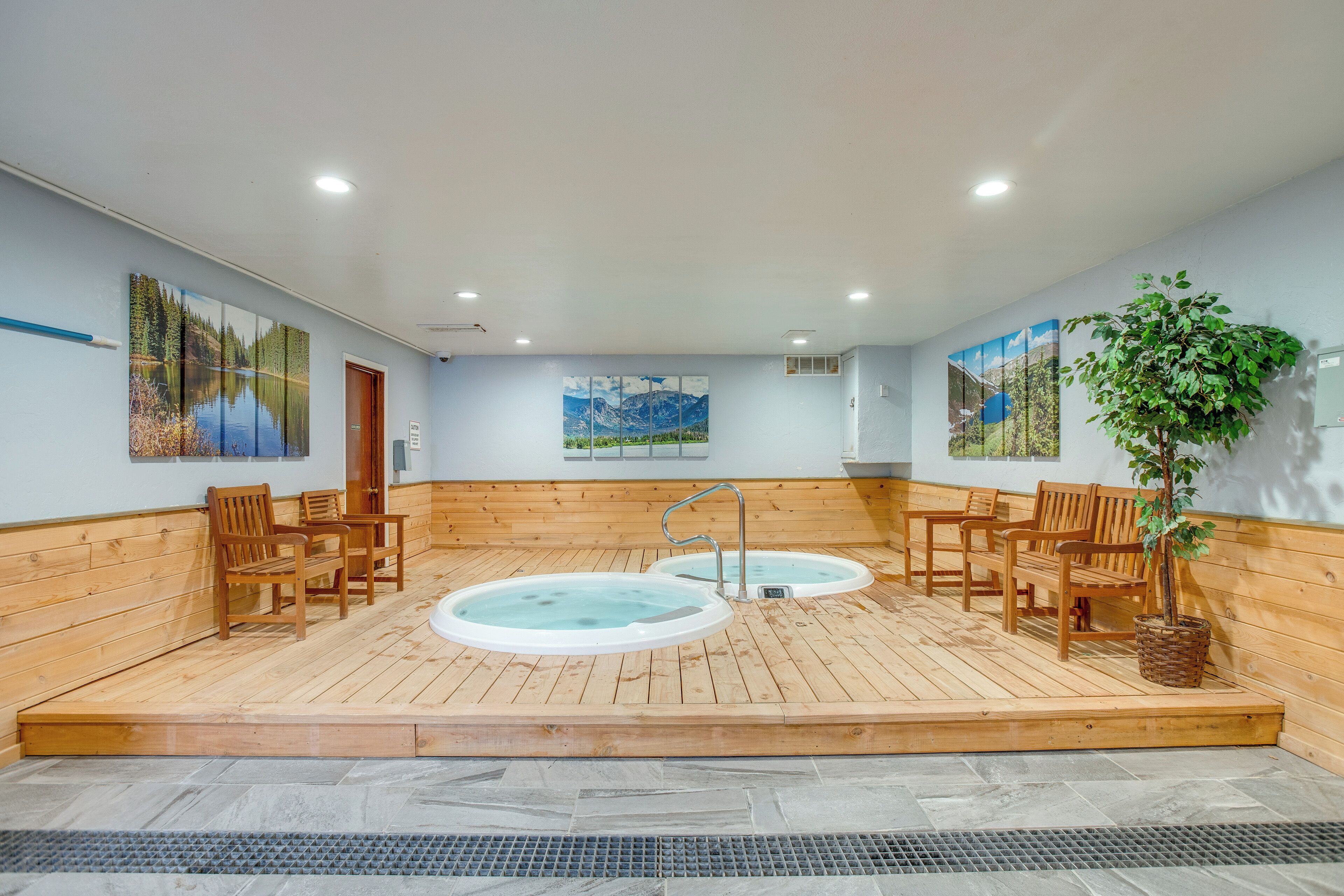 A sauna room with wooden benches, two hot tubs, and wall art.