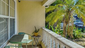 A balcony with a table and chairs, a potted plant, and a view of palm trees and a house. - Backyard Fun & Dtwn Exploring: Family Gem in Tampa (Tampa)