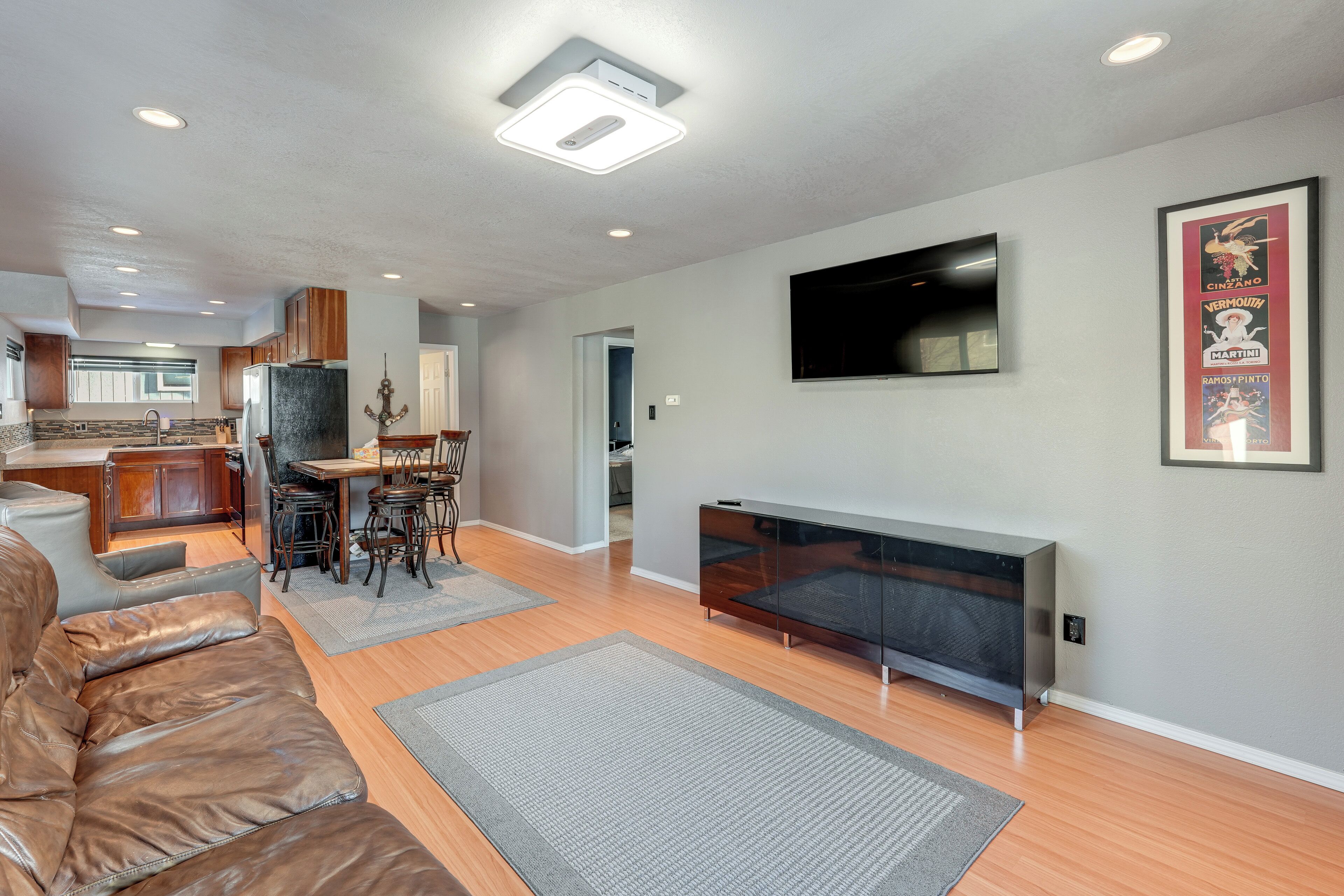 A modern living room with a leather sofa, a flat-screen TV, and a dining area with a table and chairs.