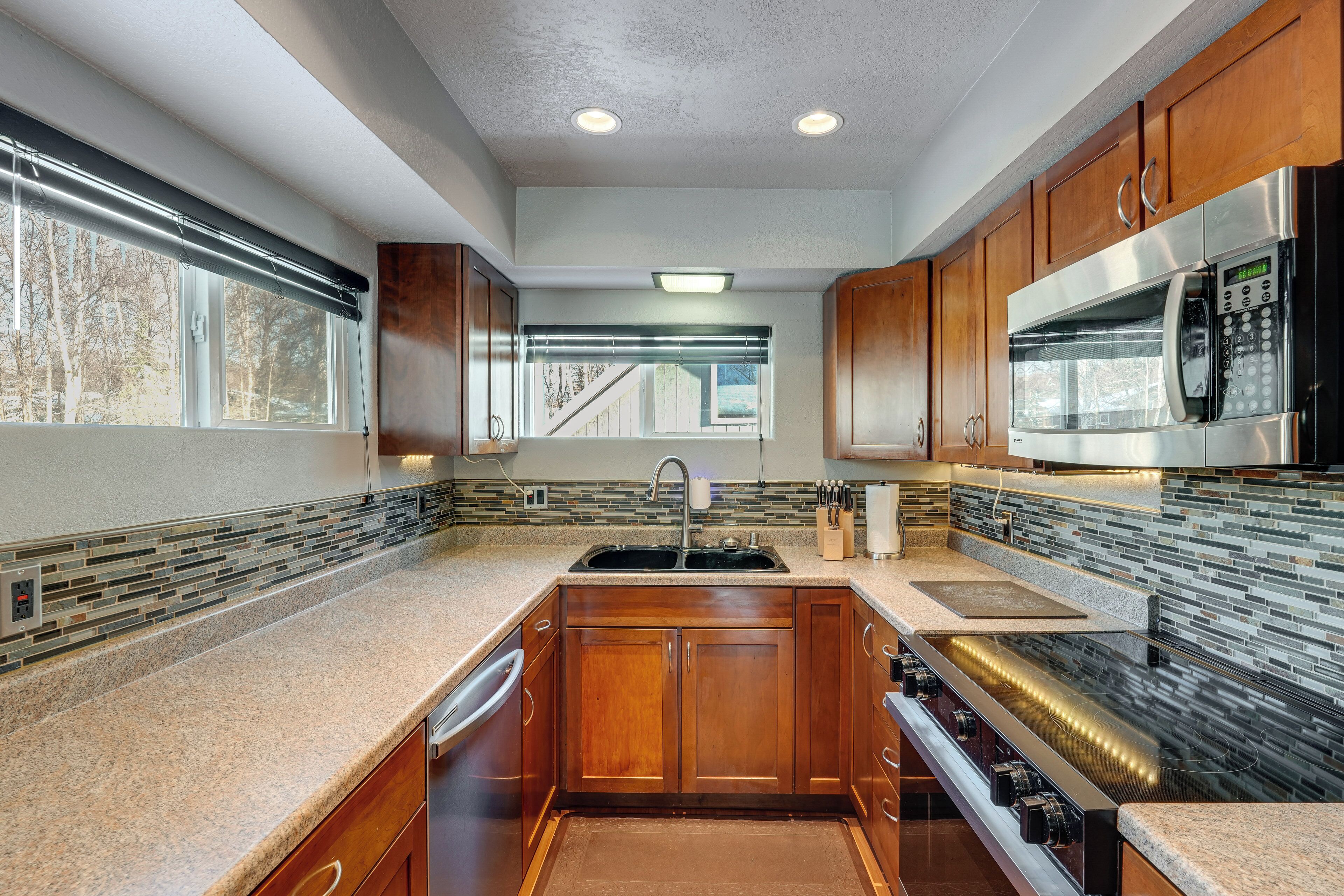 A modern kitchen with wooden cabinets, a stainless steel microwave, and a built-in oven.