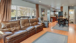 A spacious living room with a leather sofa, a dining area with a table and chairs, and a kitchen in the background. - Hike, Bike & Ski! Cozy Anchorage Townhome (Anchorage)