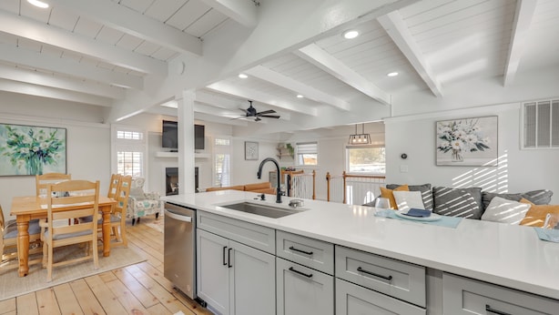 Una cocina moderna con armarios blancos, una isla grande y una zona de comedor con mobiliario de madera.