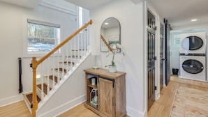 Un interior limpio y moderno con una escalera de madera, un armario empotrado y un espacio para la lavandería.