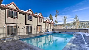 A poolside view of a two-story building with a pool, surrounded by snow-covered ground and trees. - 3 Mi to Winter Park Slopes! Unit w/ Pool & Hot Tub (Winter Park)