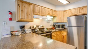 A kitchen with wooden cabinets, a stainless steel refrigerator, a microwave, a stove, and a coffee maker. - 3 Mi to Winter Park Slopes! Unit w/ Pool & Hot Tub (Winter Park)