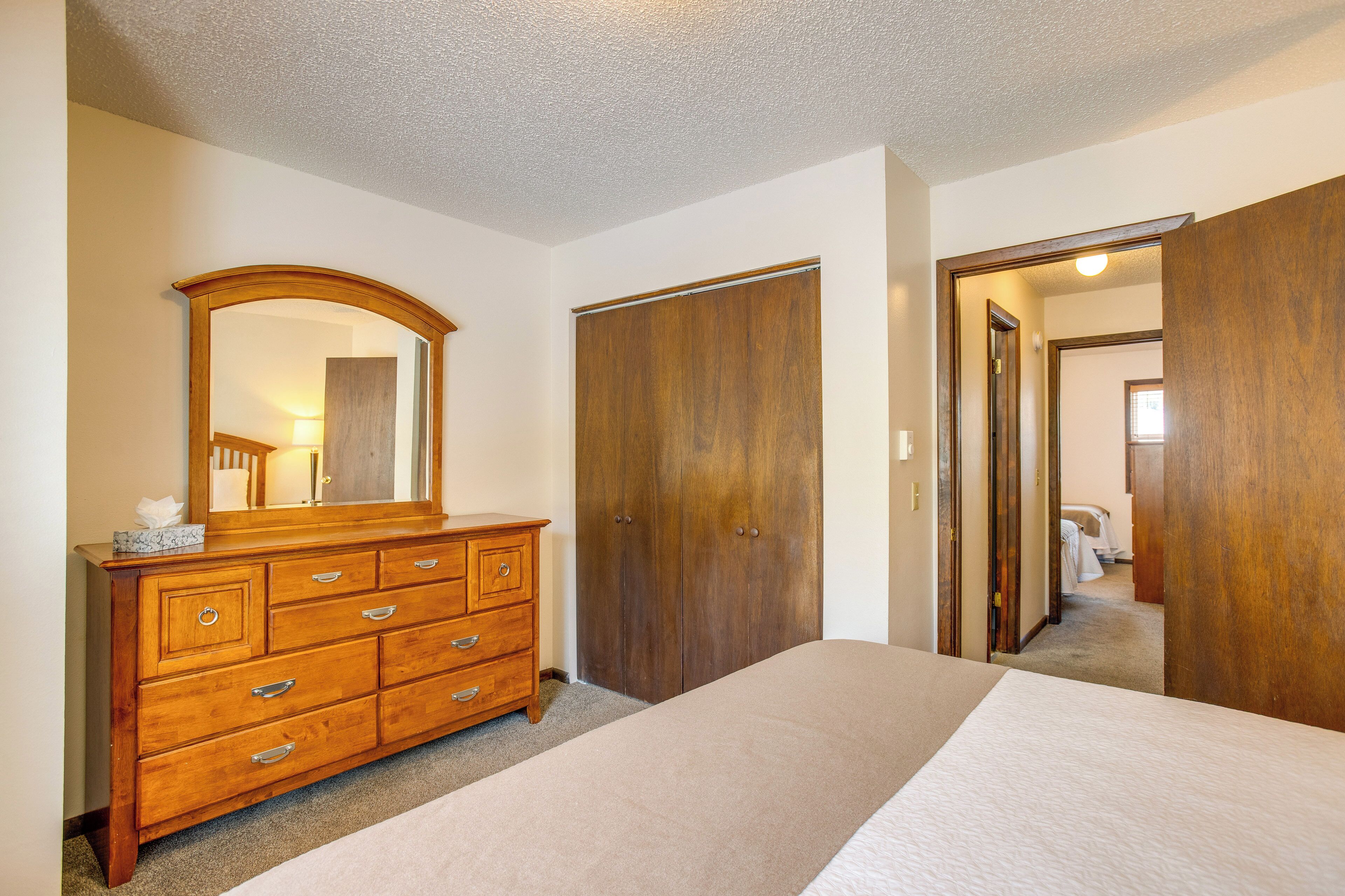 A bedroom with a wooden dresser, a large mirror, and a bed.