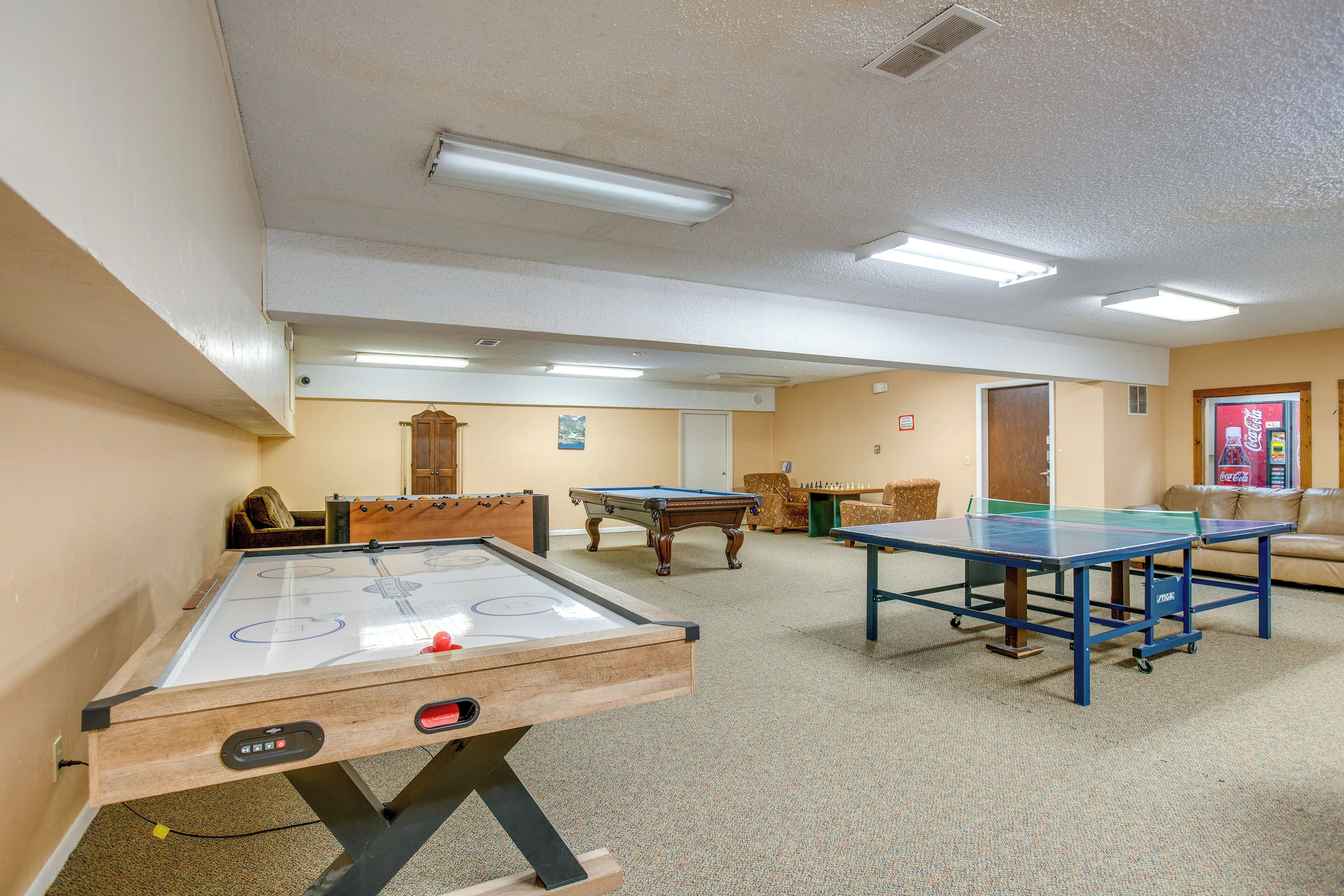 A recreational room with an air hockey table, a pool table, and a foosball table.