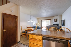 A kitchen with a granite countertop, wooden chairs, a dining table, and a built-in dishwasher. - 3 Mi to Winter Park Slopes! Unit w/ Pool & Hot Tub (Winter Park)
