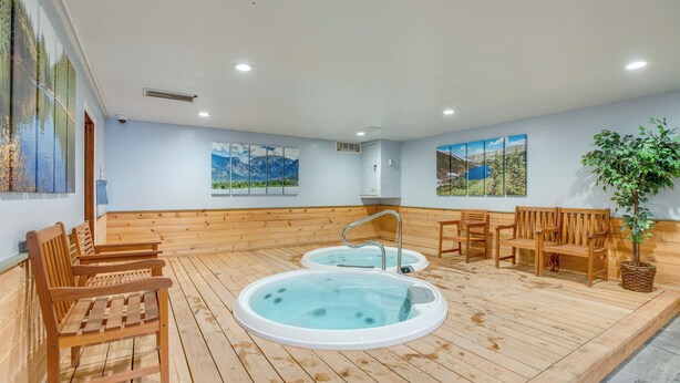 A spa area with wooden flooring, two hot tubs, wooden benches, and wall art. - 3 Mi to Winter Park Slopes! Unit w/ Pool & Hot Tub (Winter Park)