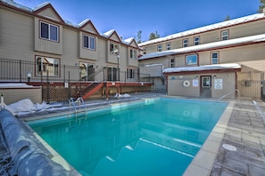 A swimming pool area with a covered deck, a staircase, and a building with multiple windows and a garage. - 3 Mi to Winter Park Slopes! Unit w/ Pool & Hot Tub (Winter Park)