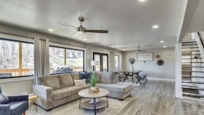 A spacious living room with a sectional sofa, a round coffee table, and a ceiling fan.