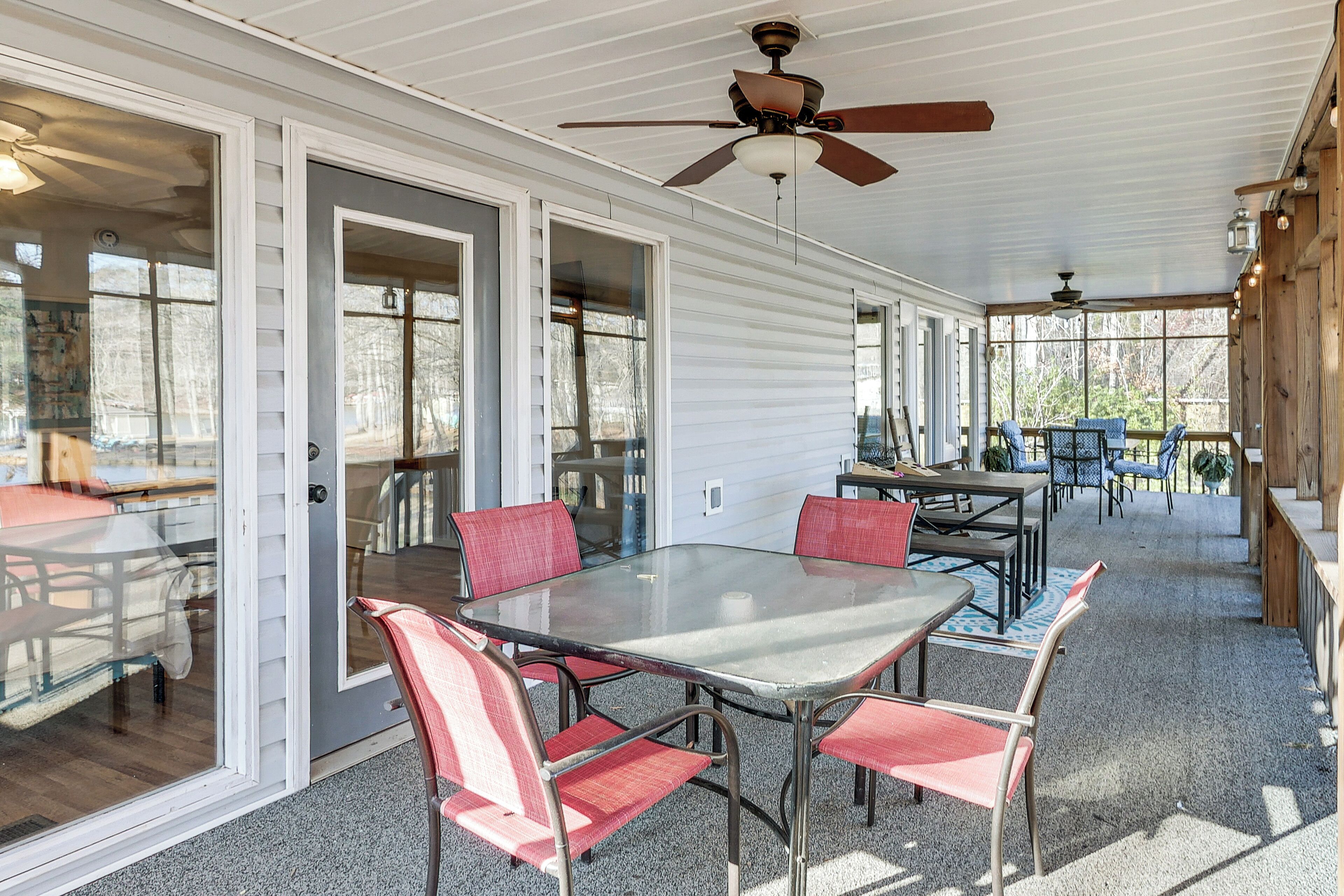A covered patio with a glass table and chairs, ceiling fans, and a view of the outdoors.