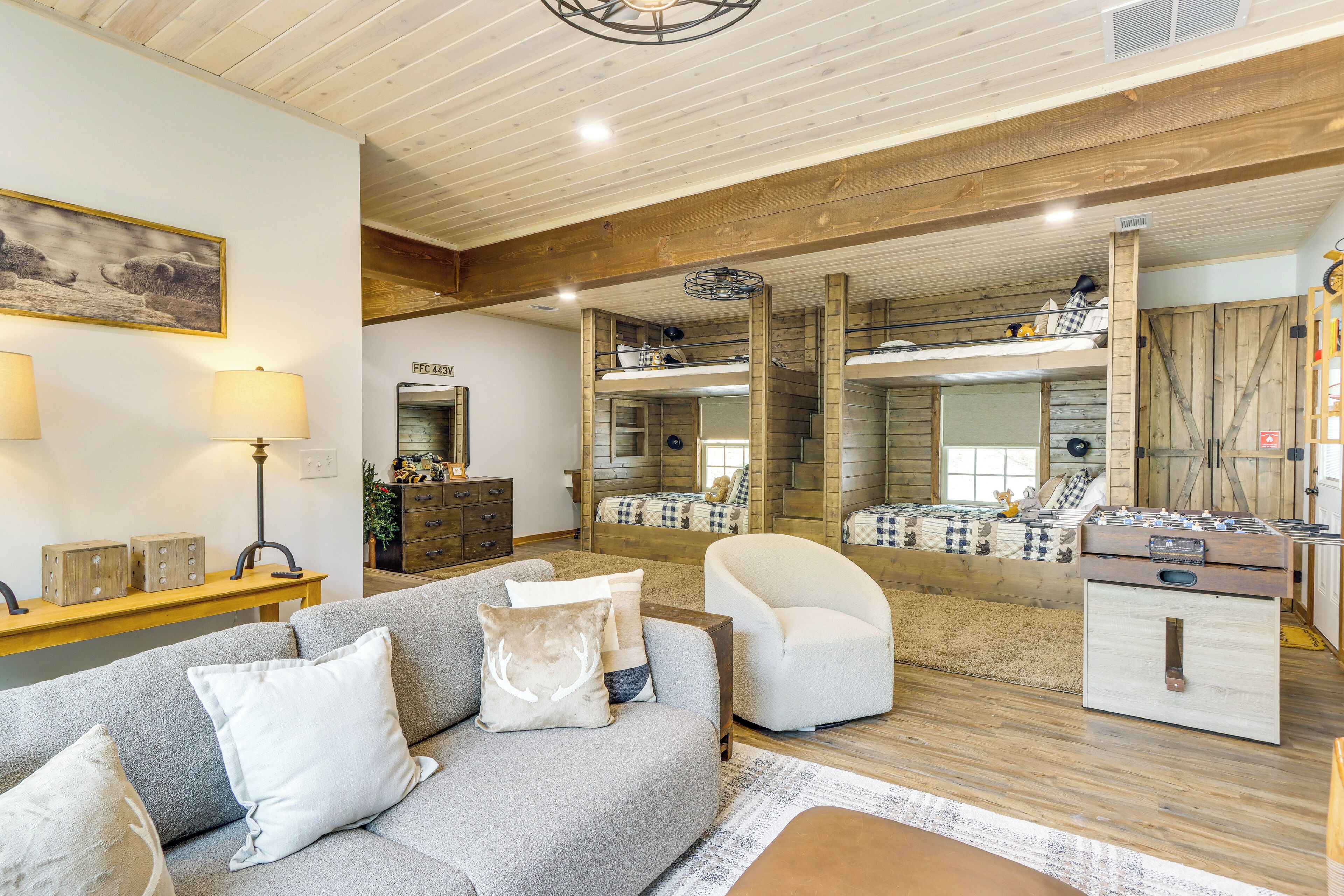 A cozy living room with a sofa, armchairs, and a foosball table.