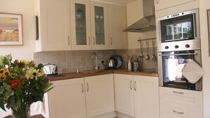 A kitchen with white cabinets, a stainless steel oven, and a wooden countertop. - The Gazebo - Winchelsea Town (East Sussex)