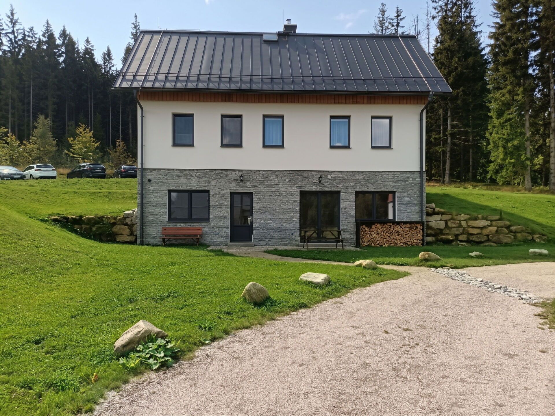 A two-story house with a stone facade, a front door, and a small porch with a bench.