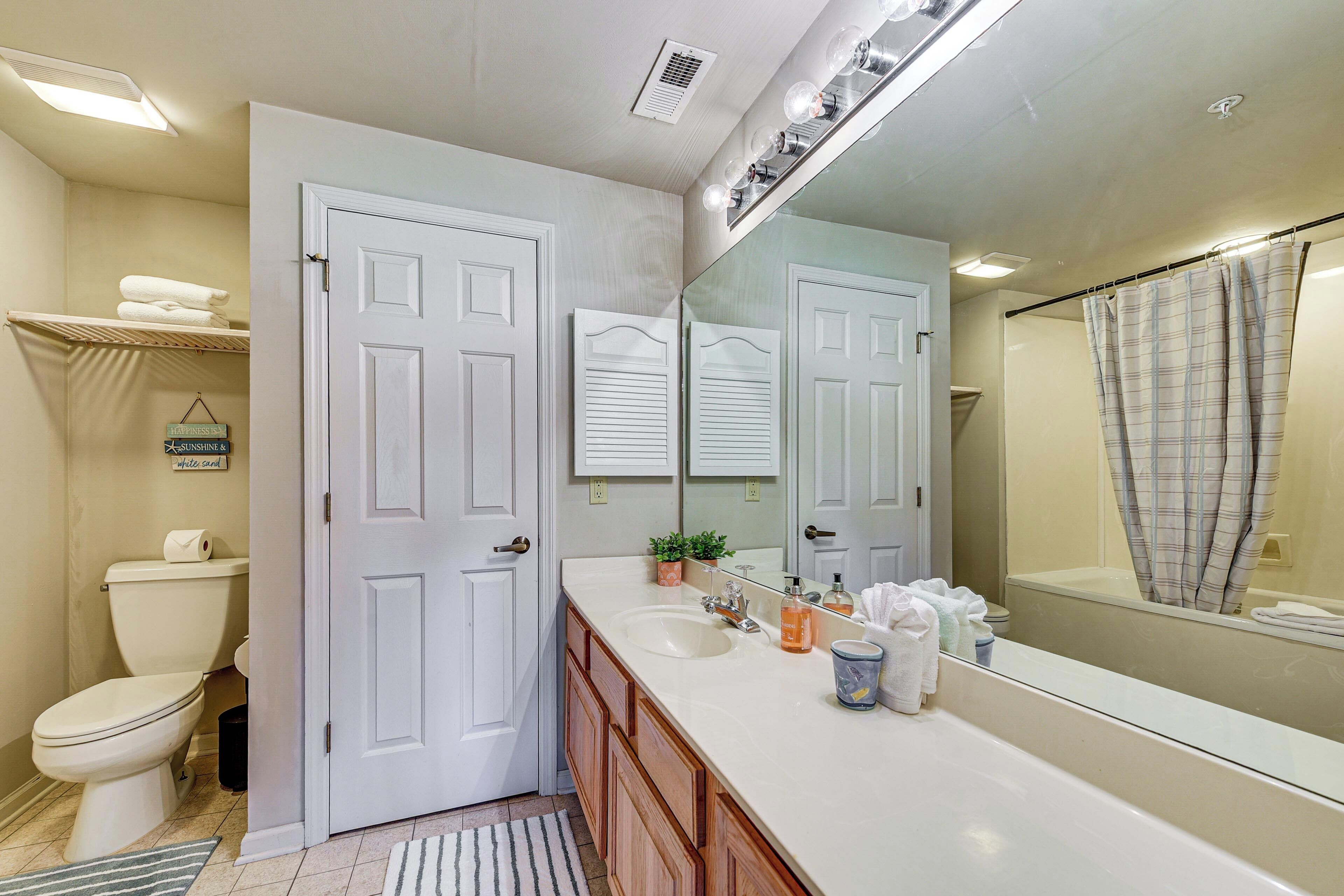 A bathroom with a white toilet, a sink, a mirror, and a shower curtain.