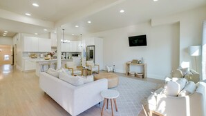 A spacious living area with a white sofa, a round ottoman, and a coffee table. There is a kitchen in the background with white cabinets and a stainless steel refrigerator. - Heart of Bay View Neighborhood! Modern Retreat (Milwaukee)
