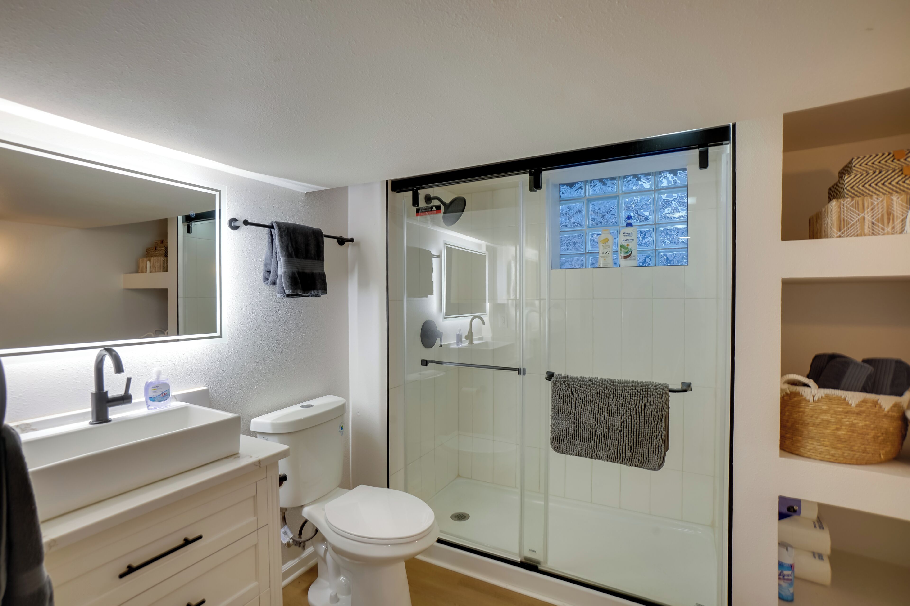 A modern bathroom with a glass-enclosed shower, a white sink, and a toilet.