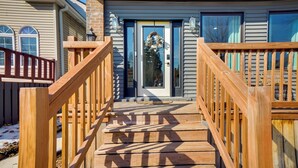 A wooden staircase leading to a front door with a wreath, flanked by two windows and a brick wall. - Heart of Bay View Neighborhood! Modern Retreat (Milwaukee)