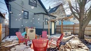 A backyard with a wooden deck, a tree, and a patio area with red chairs and a table. - Heart of Bay View Neighborhood! Modern Retreat (Milwaukee)