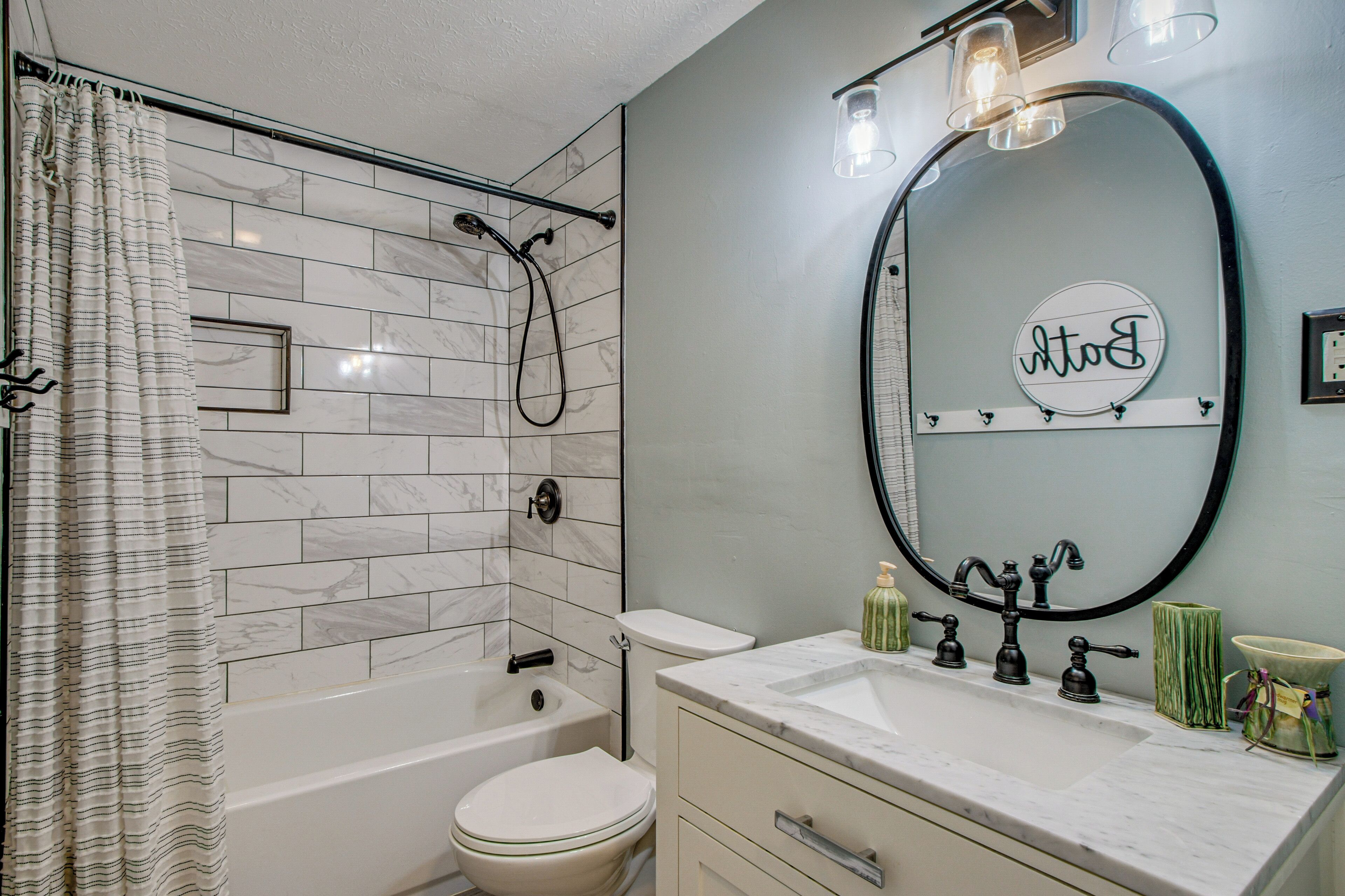 A bathroom with a bathtub, toilet, and vanity with a mirror.