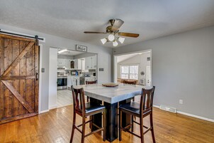 A dining area with a large table, four chairs, and a ceiling fan.