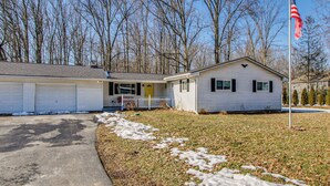 A single-story house with a garage, a front porch, and a flagpole with an American flag. - Peaceful Retreat w/ Private Hot Tub in New Albany (New Albany)