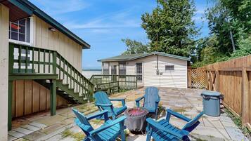 A patio with blue Adirondack chairs, a small fire pit, and a wooden fence.
