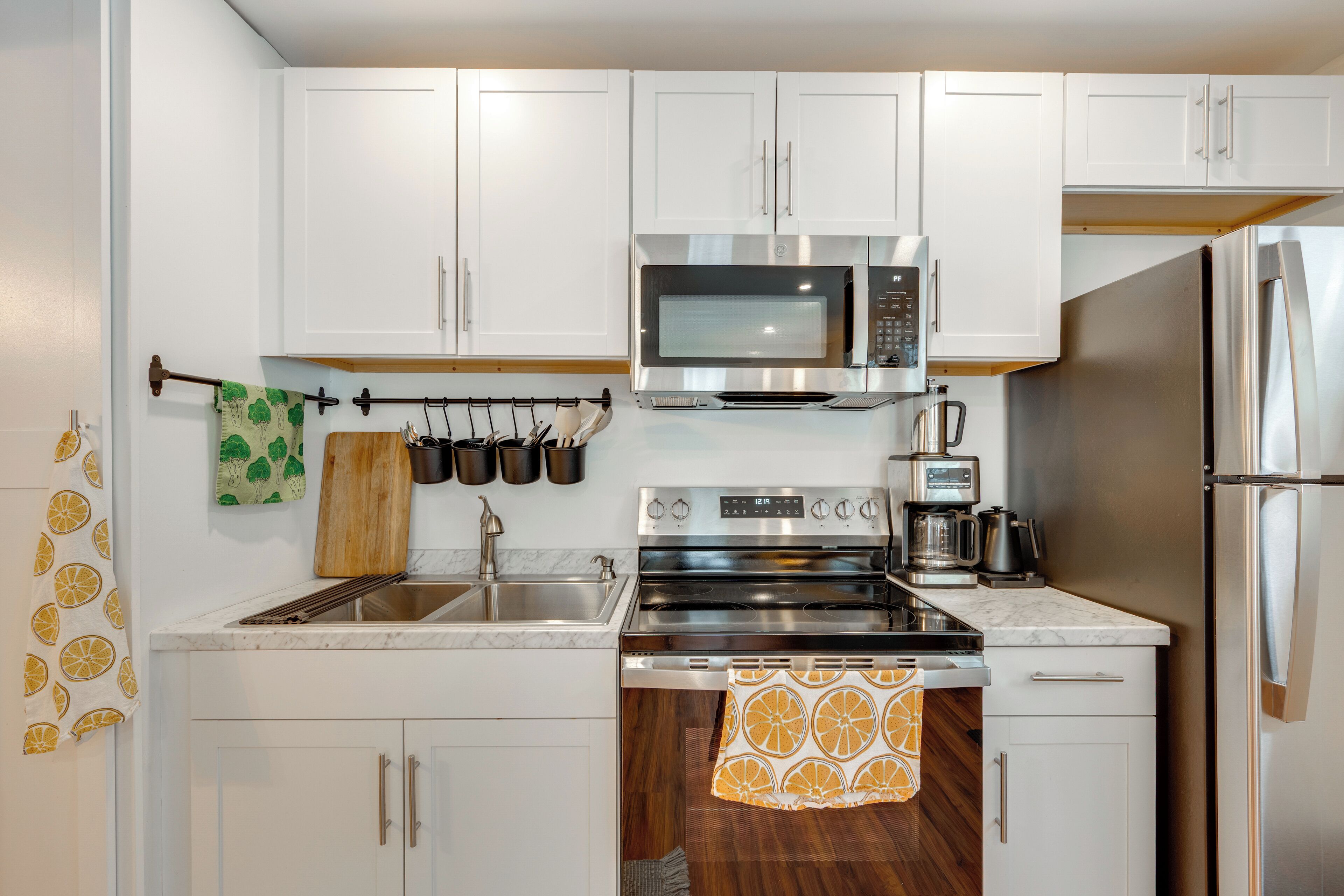 A modern kitchen with white cabinets, stainless steel appliances, and a wooden countertop.
