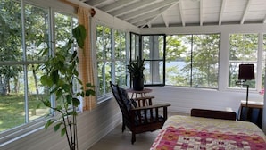 Ein Zimmer mit einem großen Bett, einem Sessel, einem Tisch und einem Blumentopf.
