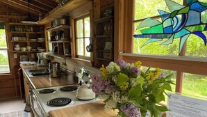 Eine Holz-Küche mit Herd, Regalen und einer Blumenvase auf der Arbeitsfläche.