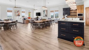 Une cuisine spacieuse avec des meubles de couleur sombre, un grand îlot central et un éclairage moderne suspendu au plafond.