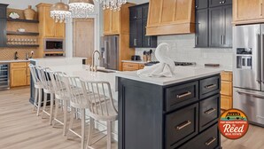 Une cuisine moderne avec des meubles en bois, des appareils en acier inoxydable et un îlot central doté de tabourets de bar.