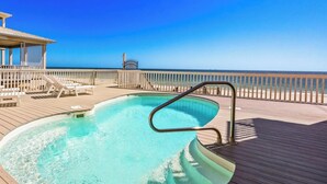 Area piscina con vista sull'oceano, un pontile in legno e una postazione di salvataggio.