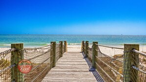 Una passerella di legno che conduce a una spiaggia sotto un cielo azzurro e limpido.