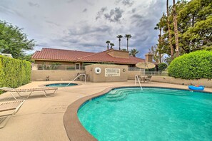 A swimming pool with lounge chairs, a lifeguard tower, and palm trees in the background. - Palm Desert Gem w/ Outdoor Oasis & Resort Perks! (Palm Desert)