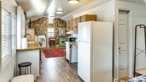 A compact kitchen with a stone accent wall, wooden cabinets, a white refrigerator, and a red rug. - 6 Mi to Clift Farm! Pet-friendly Guesthouse (Harvest)