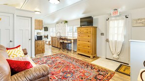 A spacious living area with a leather couch, a patterned rug, and a wooden cabinet. - 6 Mi to Clift Farm! Pet-friendly Guesthouse (Harvest)
